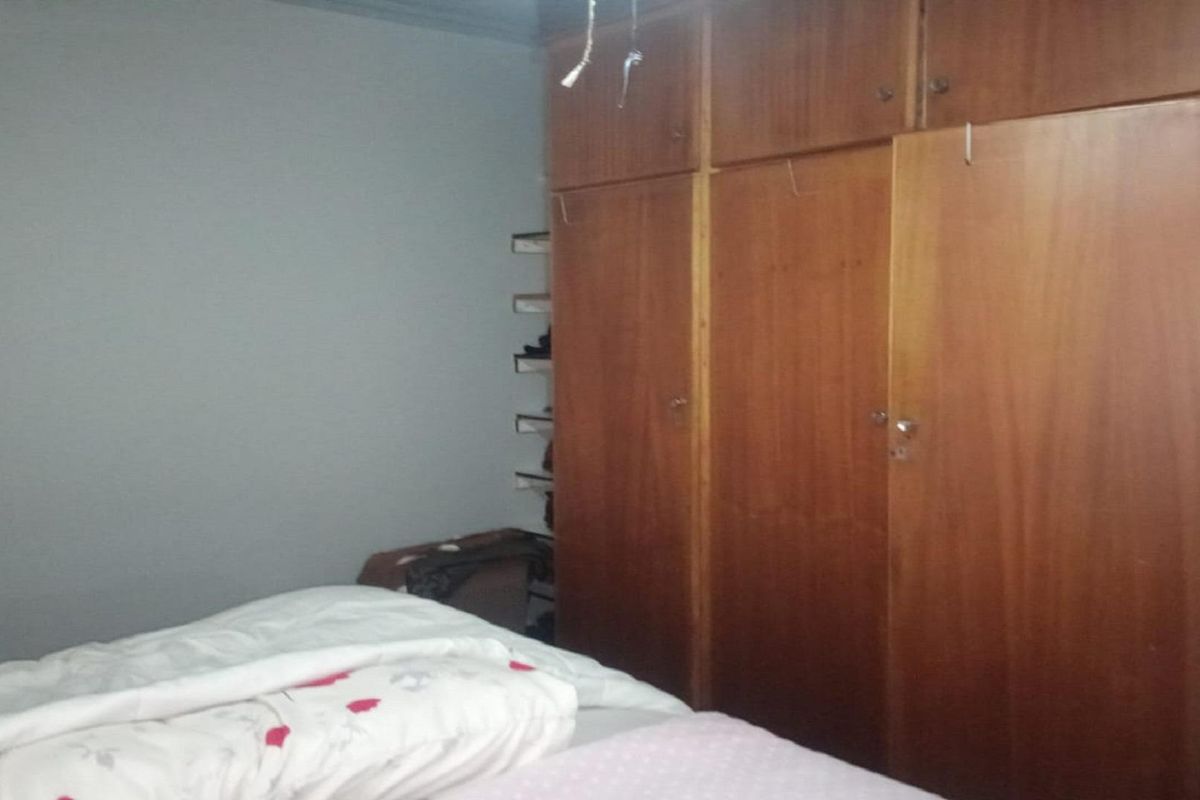A bedroom featuring built-in wooden wardrobes with overhead storage compartments.