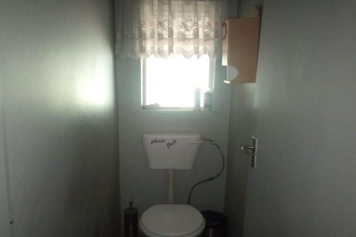A compact, functional guest toilet featuring a standard white ceramic toilet suite and a small window for natural light.