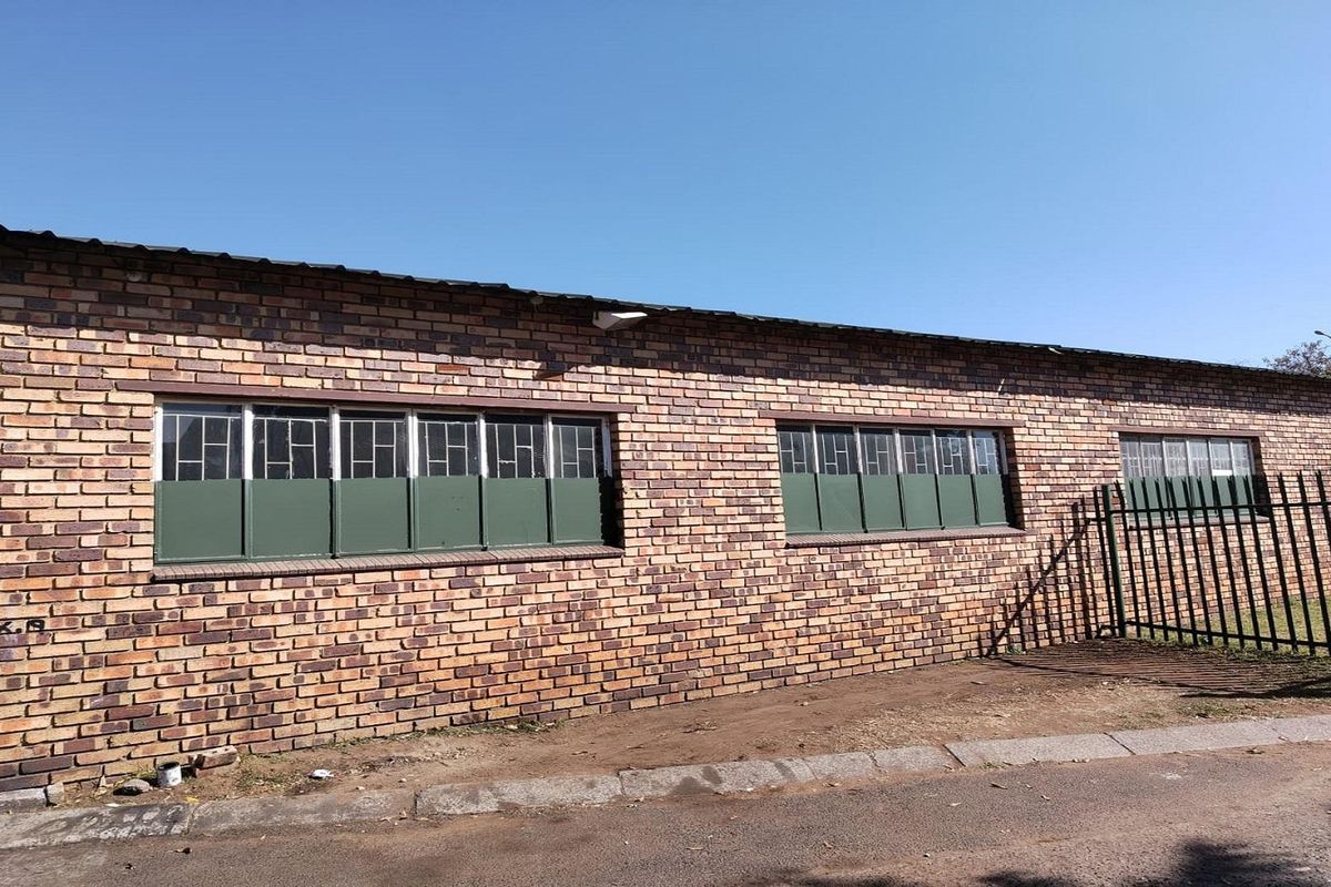 Exterior view of a brick building featuring metal-framed windows and a perimeter security fence.