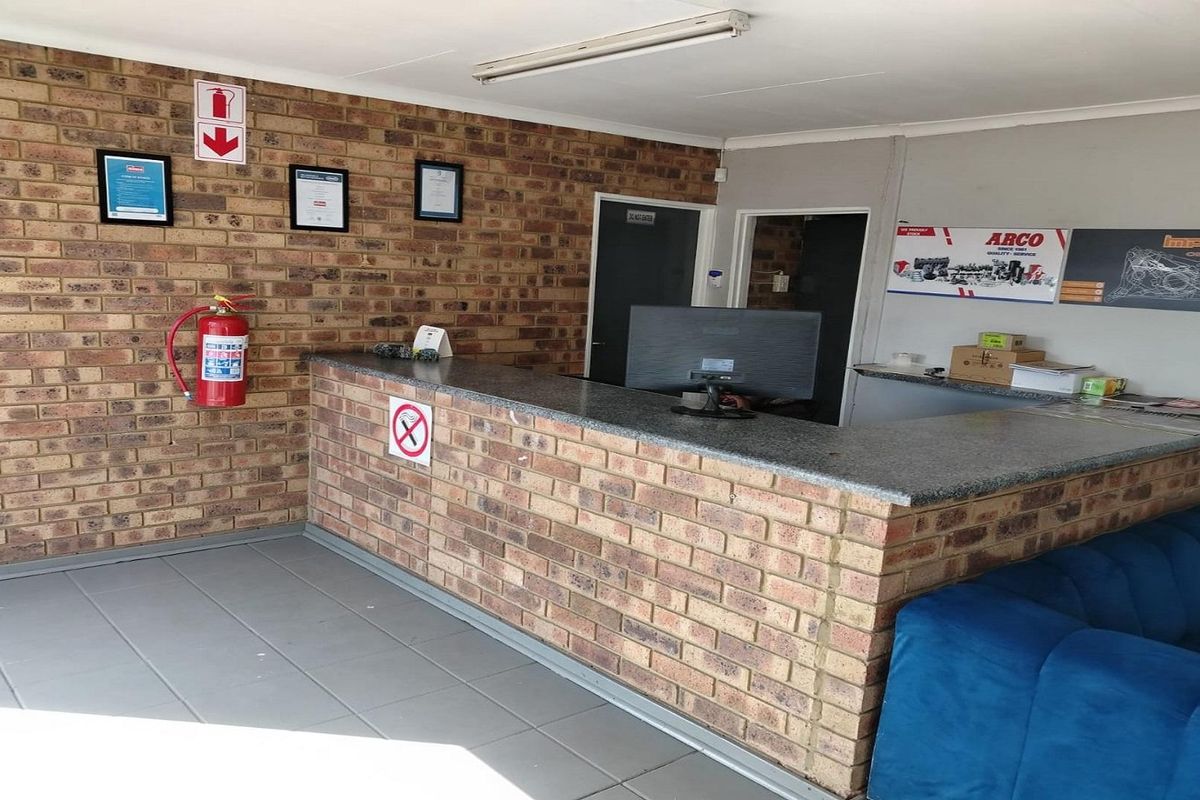 A functional reception or utility area featuring a brick-faced service counter, tiled flooring, and exposed brick wall detailing.