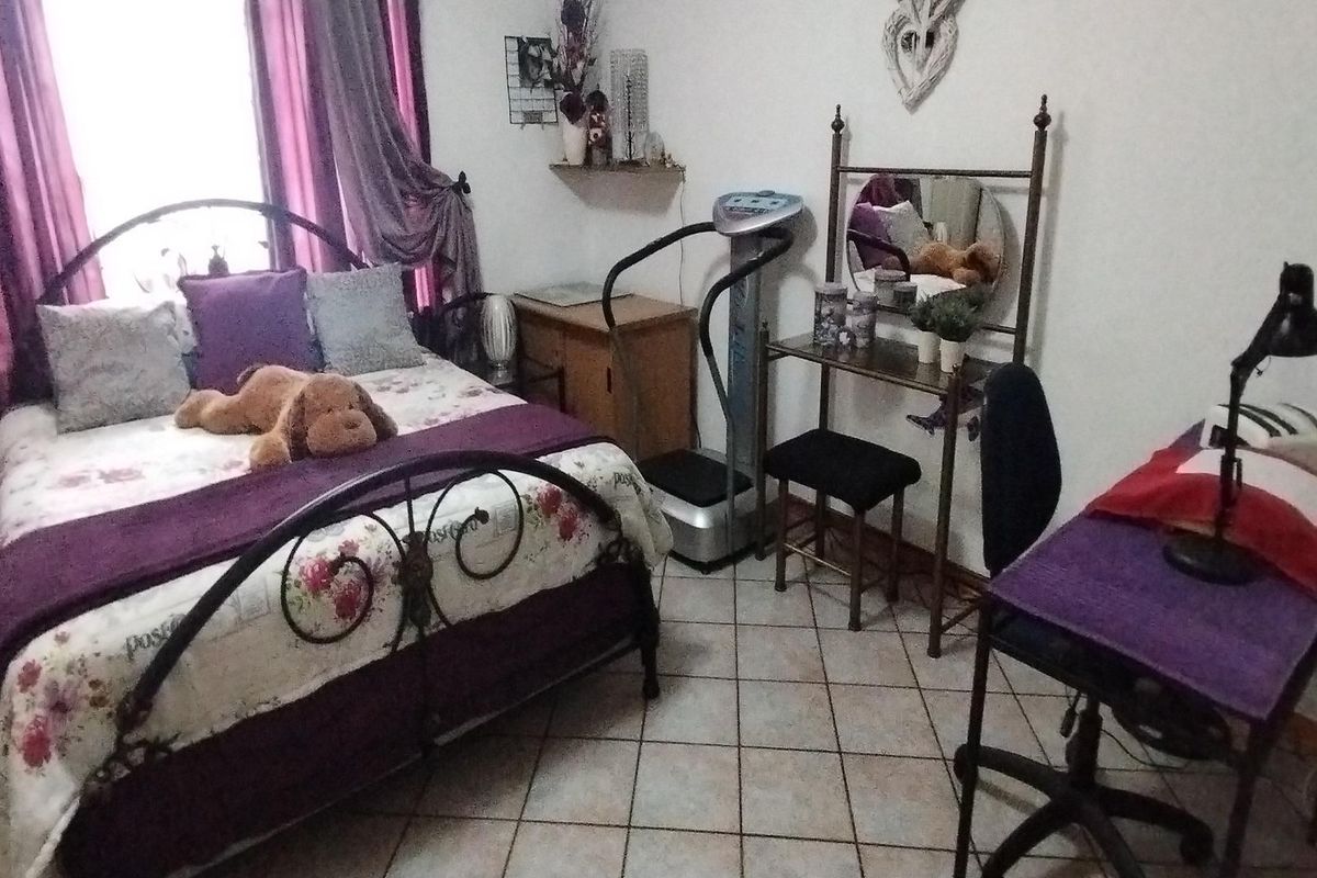 A bedroom featuring tiled flooring and a window with curtains.