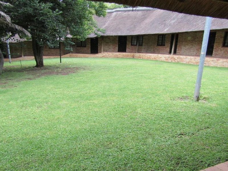 A view of a central lawn area surrounded by a brick-built residential building with a traditional thatched roof.