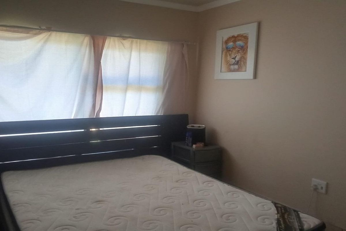 A bedroom featuring neutral wall tones and a window with curtain treatments.