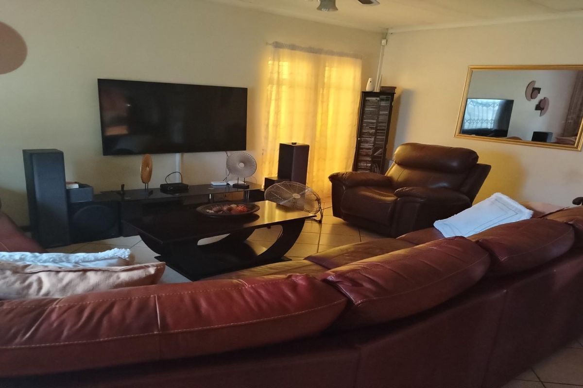 A comfortable living room featuring tiled flooring and a wall-mounted television setup, providing a functional space for relaxation and entertainment.