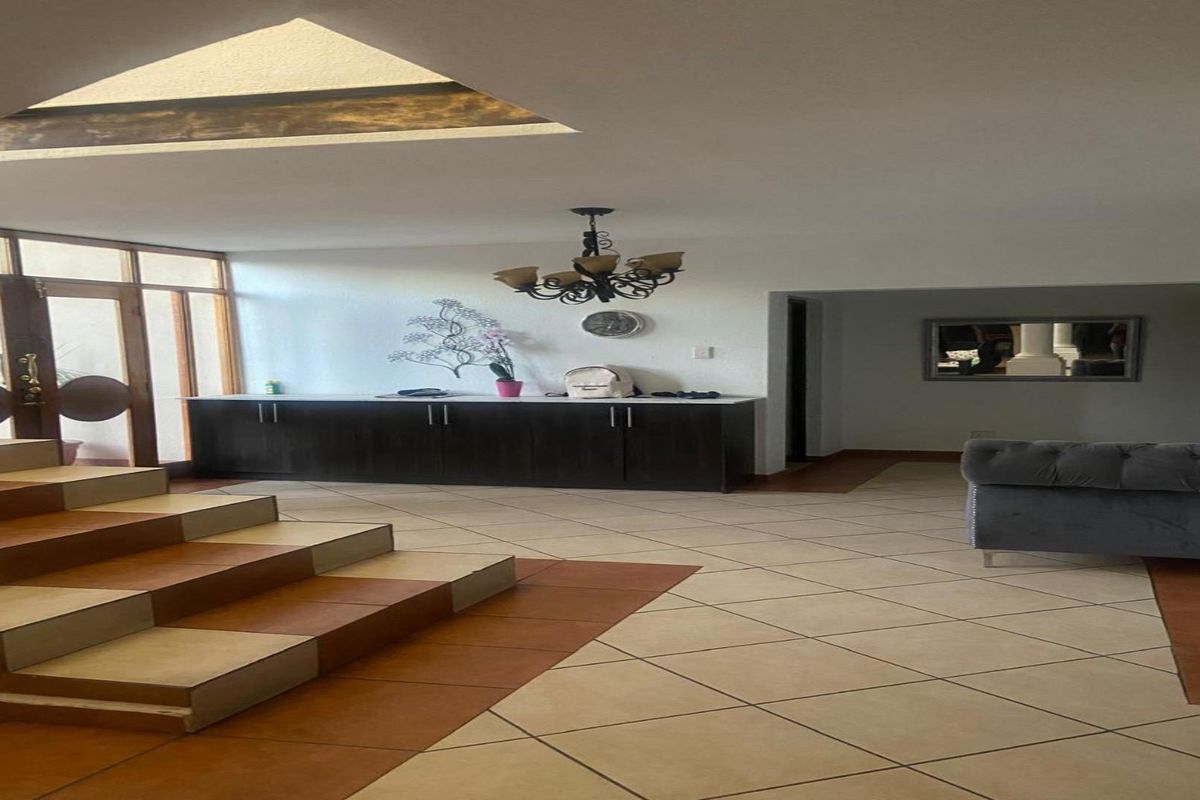 Spacious open-plan living area featuring a unique split-level staircase, built-in cabinetry, and a large skylight providing natural illumination.