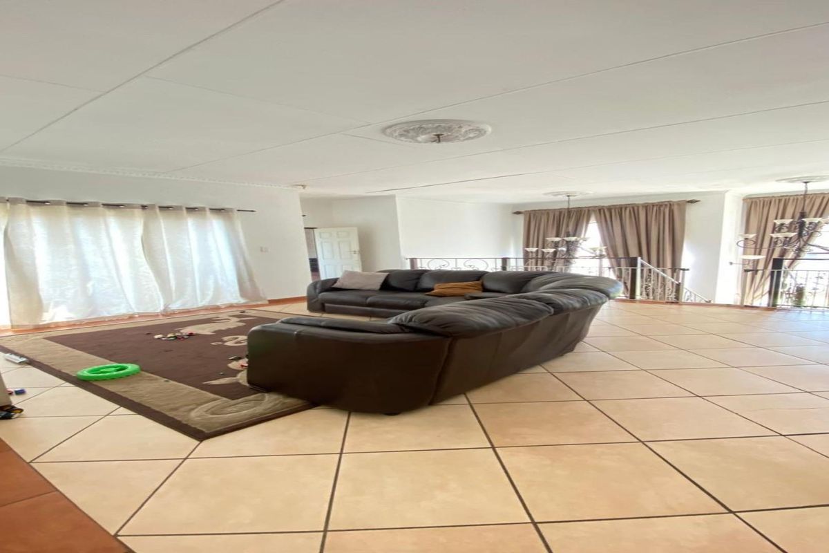 Spacious open-plan living area featuring tiled flooring, decorative ceiling roses, and large windows allowing for ample natural light.