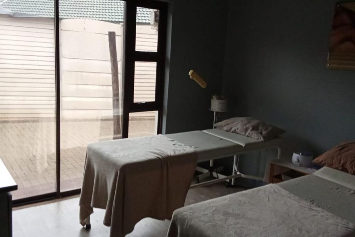 A functional room currently utilized as a treatment space, featuring large sliding glass doors that provide direct access to the paved outdoor area.