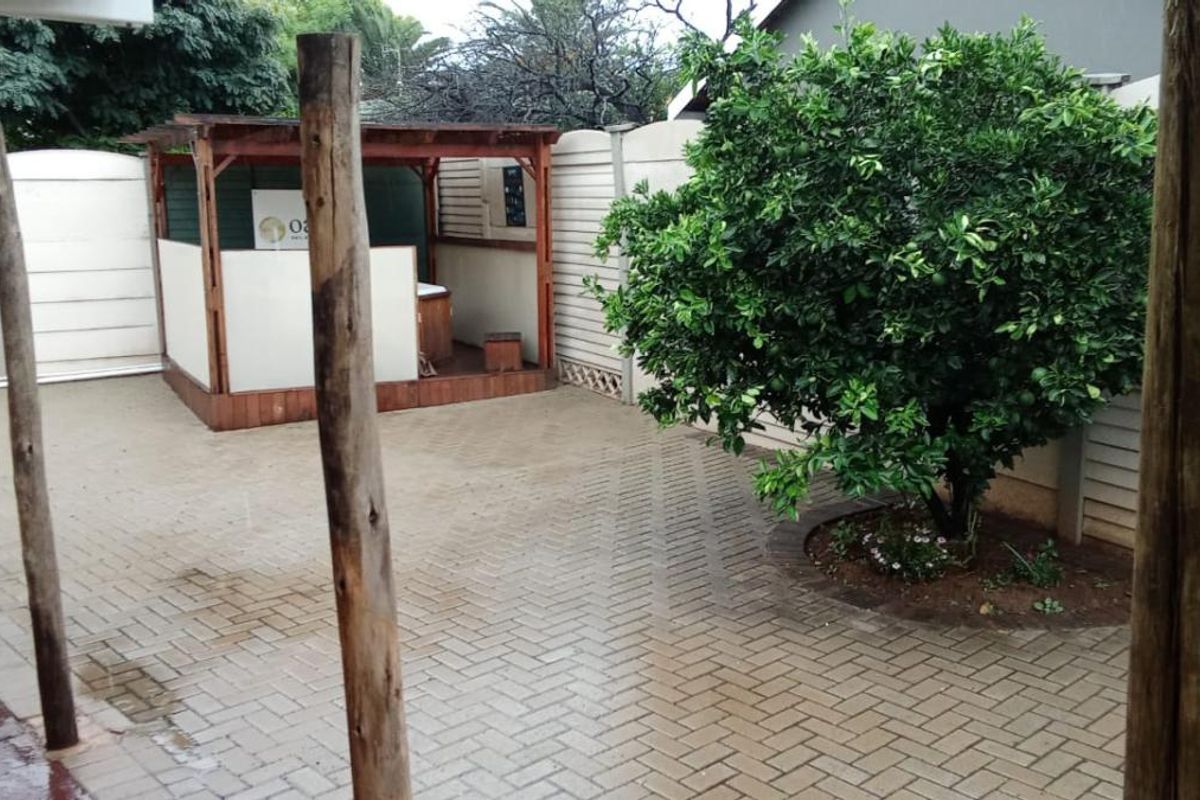 A paved rear courtyard featuring a wooden gazebo structure and established garden tree, enclosed by perimeter fencing.