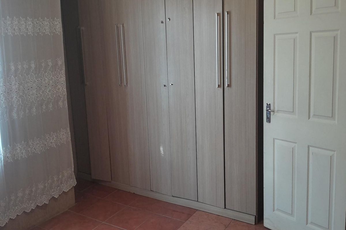 A bedroom featuring built-in wooden cabinetry with modern handles and tiled flooring.