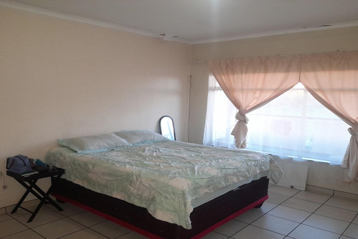 A spacious bedroom featuring tiled flooring and large windows with natural light, providing a neutral canvas for personalization.