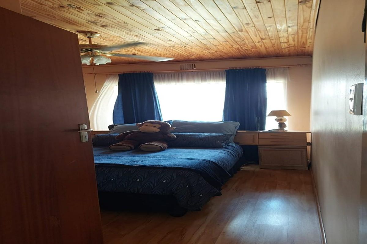 A bedroom featuring a timber-clad ceiling, laminate flooring, and a large window providing natural light.