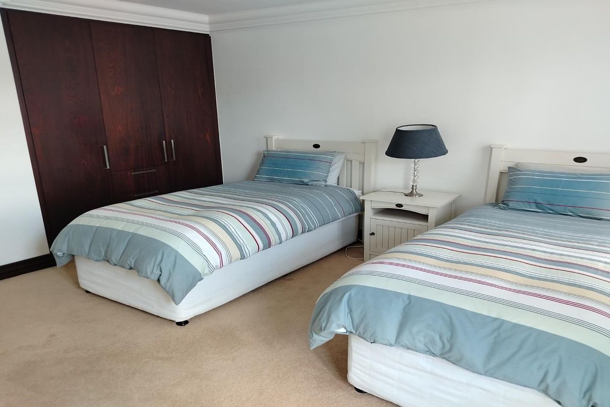 A bedroom featuring neutral carpeting, white walls, and built-in dark wood cabinetry providing ample storage space.