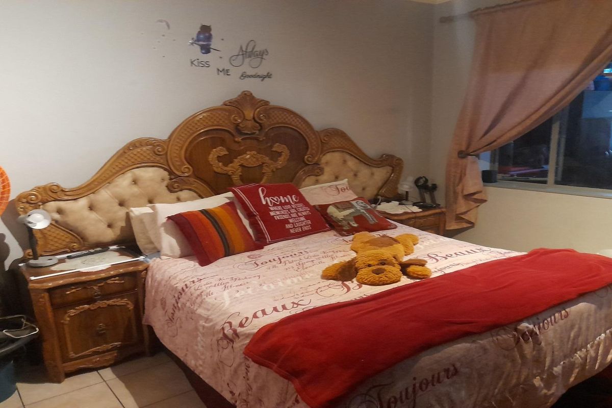 A bedroom featuring tiled flooring and a window with curtain treatments.