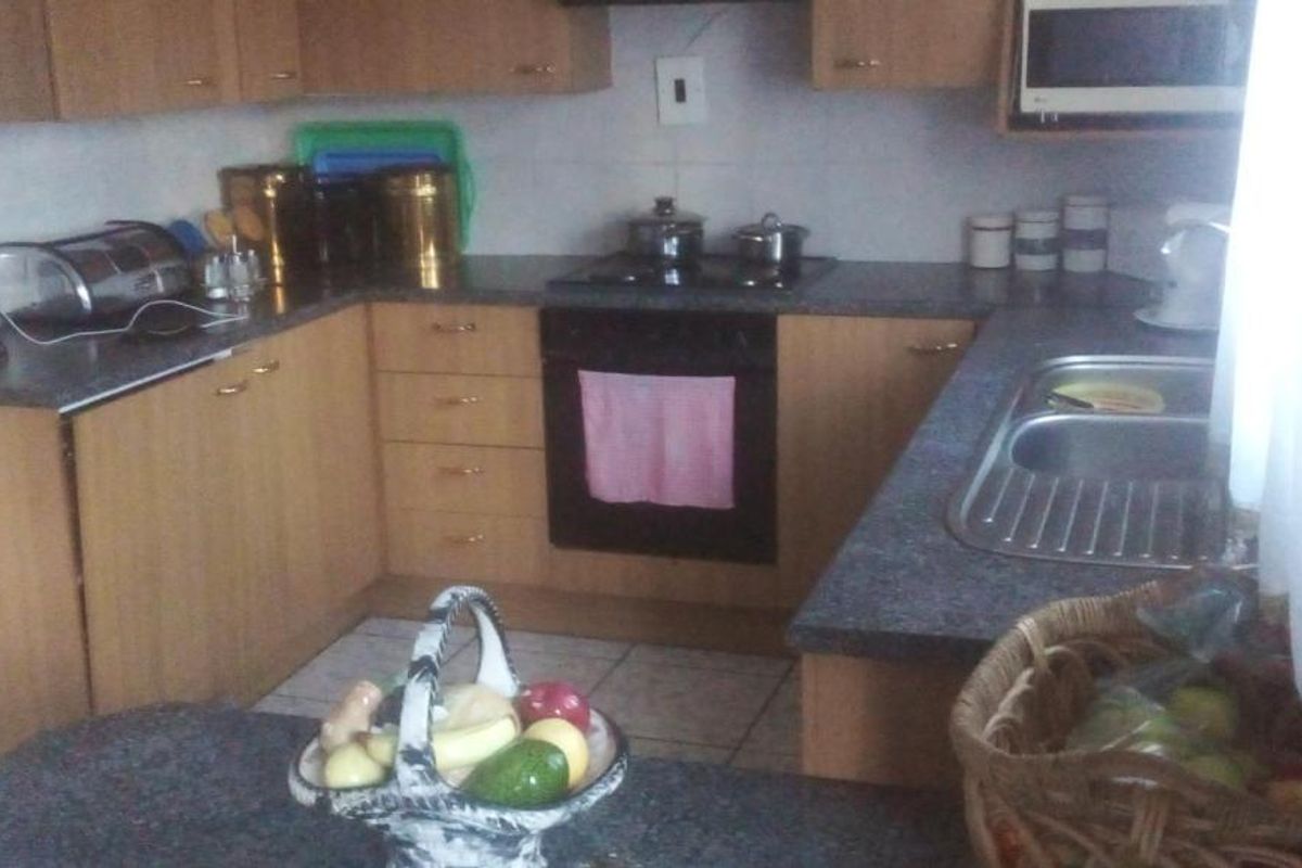 A functional kitchen featuring laminate cabinetry, dark countertops, a built-in oven, and a hob with an extractor fan.