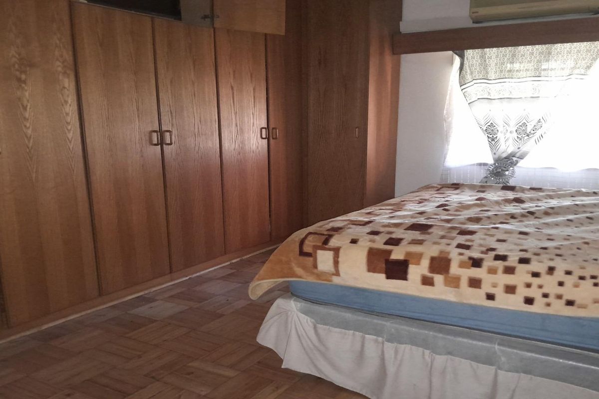 Bedroom featuring extensive built-in wooden cabinetry and parquet flooring, offering ample storage space.