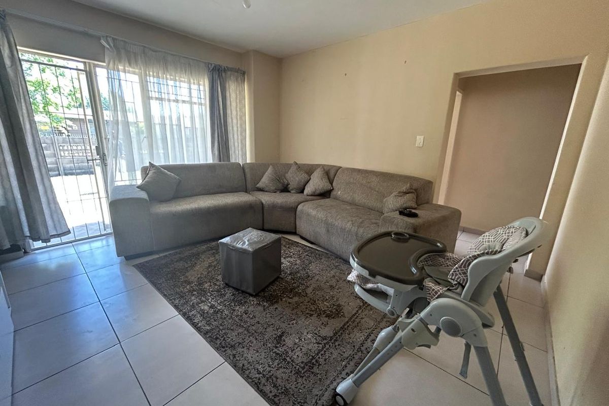 A spacious living room featuring neutral floor tiles and a large sliding glass door providing access to the exterior.