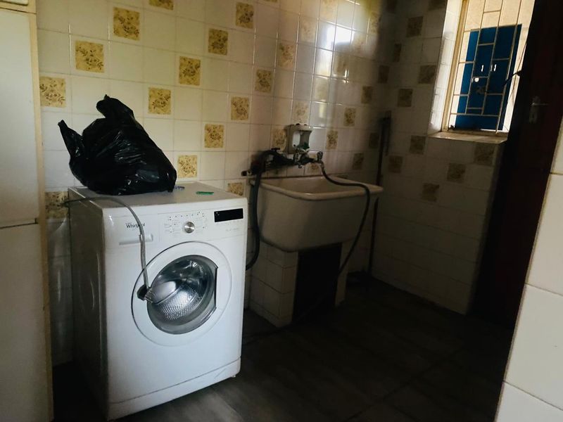 A functional laundry area featuring a utility sink, tiled walls, and tiled flooring, providing a practical space for household washing tasks.