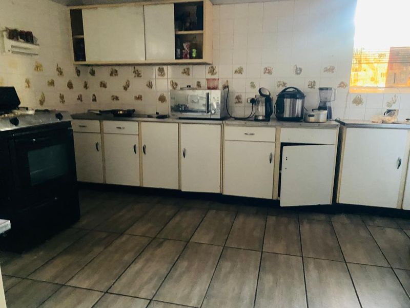A dated kitchen featuring tiled flooring, a tiled backsplash, and built-in cabinetry with a freestanding oven.