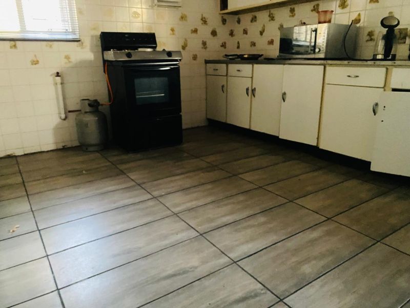 A dated kitchen featuring tiled flooring, built-in cabinetry, and a gas stove, offering significant potential for modernization and renovation.