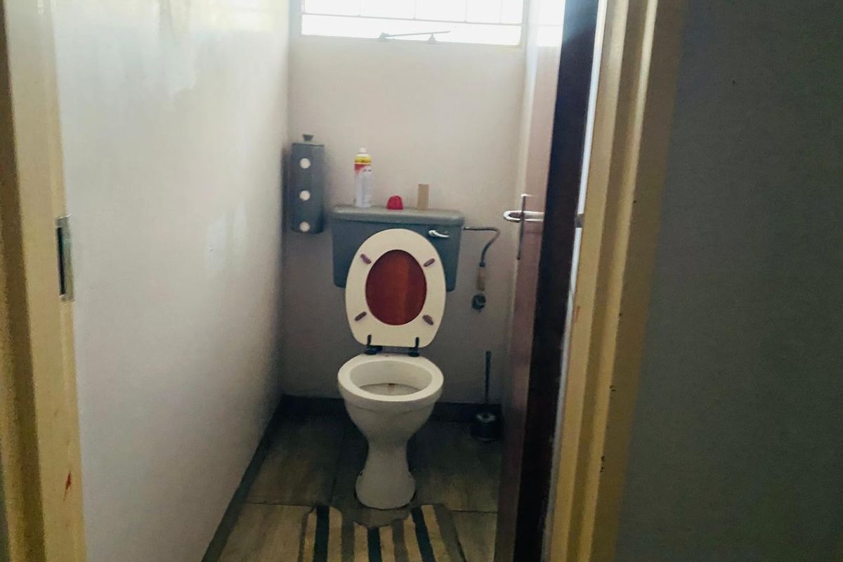 A small, functional bathroom featuring a standard toilet and cistern, with a window providing natural light.