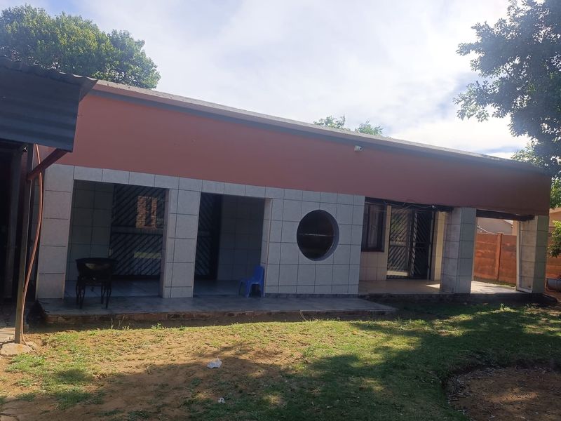 Rear view of the house featuring a covered patio area with tiled flooring, security gates, and a distinctive circular window design.