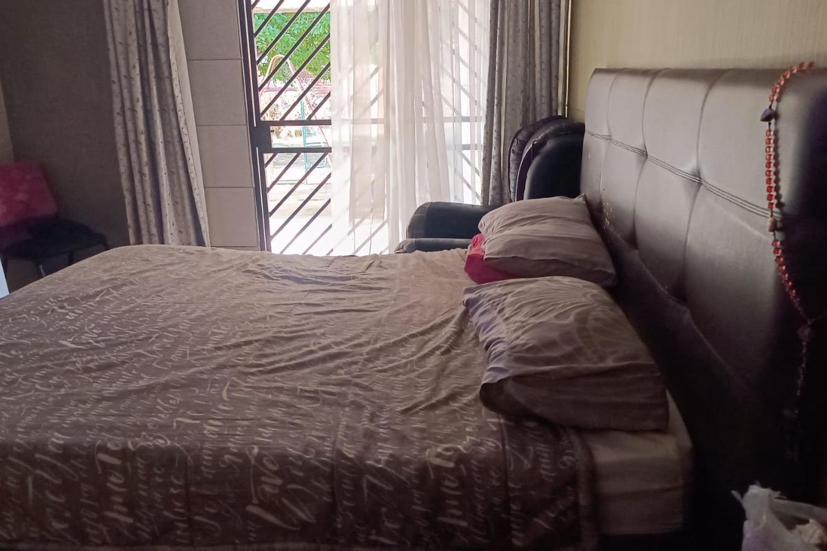A bedroom featuring a sliding glass door with an integrated security gate, providing access to the exterior.