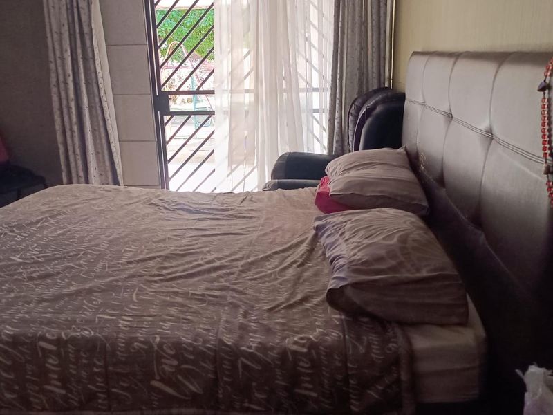 A bedroom featuring a sliding glass door with an integrated security gate, providing access to the exterior.