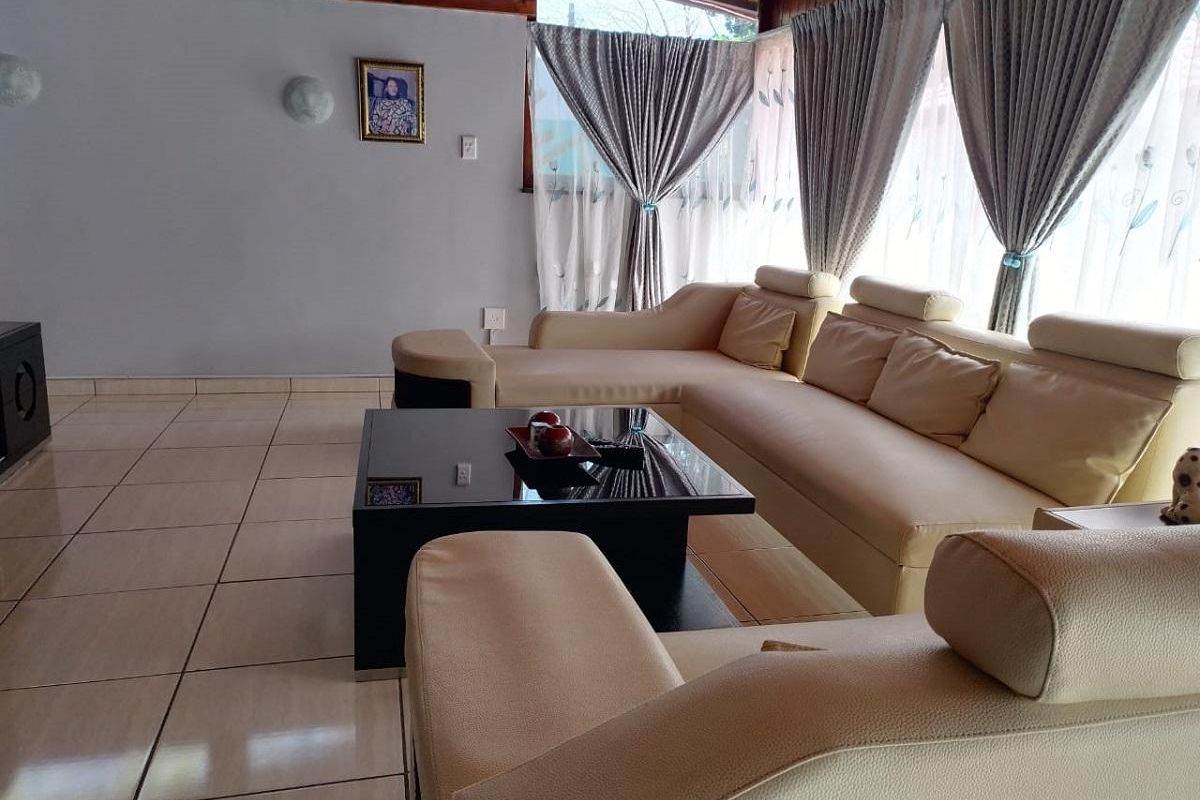 A spacious living room featuring large windows, tiled flooring, and a vaulted timber-paneled ceiling, providing a bright and comfortable atmosphere.