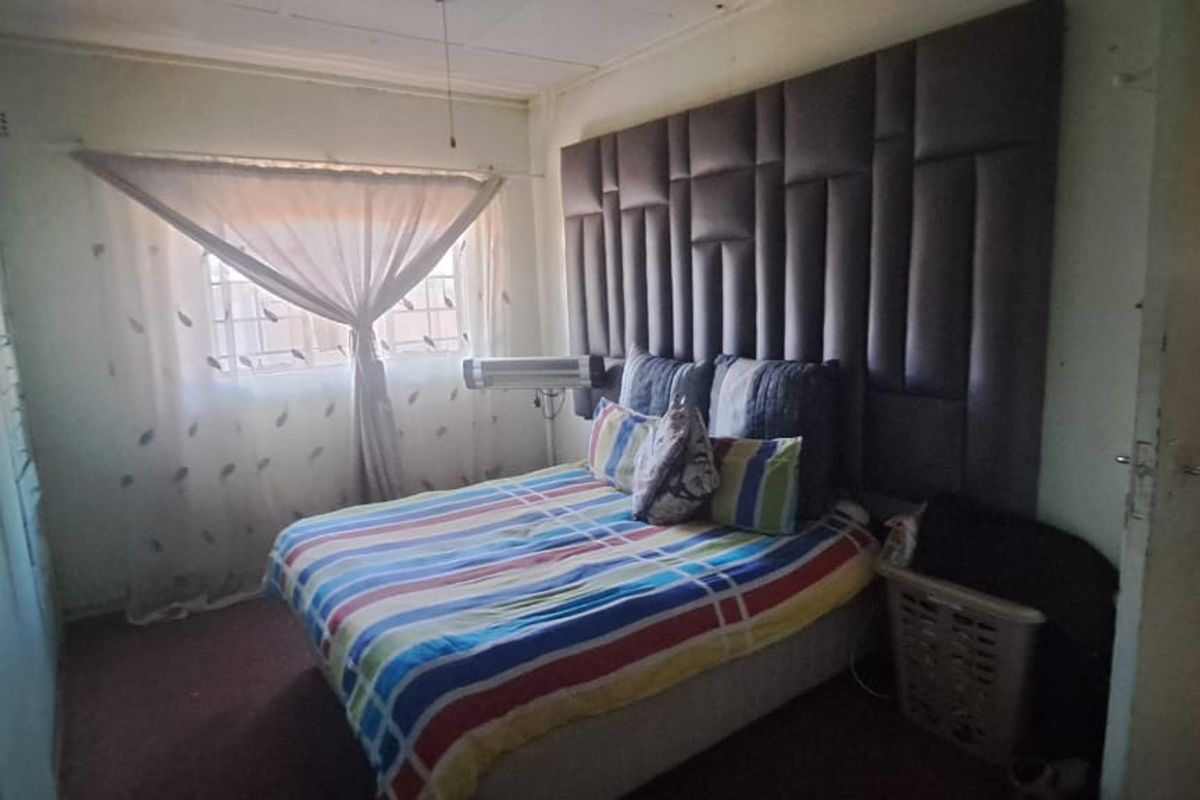 A bedroom featuring built-in wardrobes and a large upholstered headboard, requiring cosmetic updates to improve the overall finish and appeal.