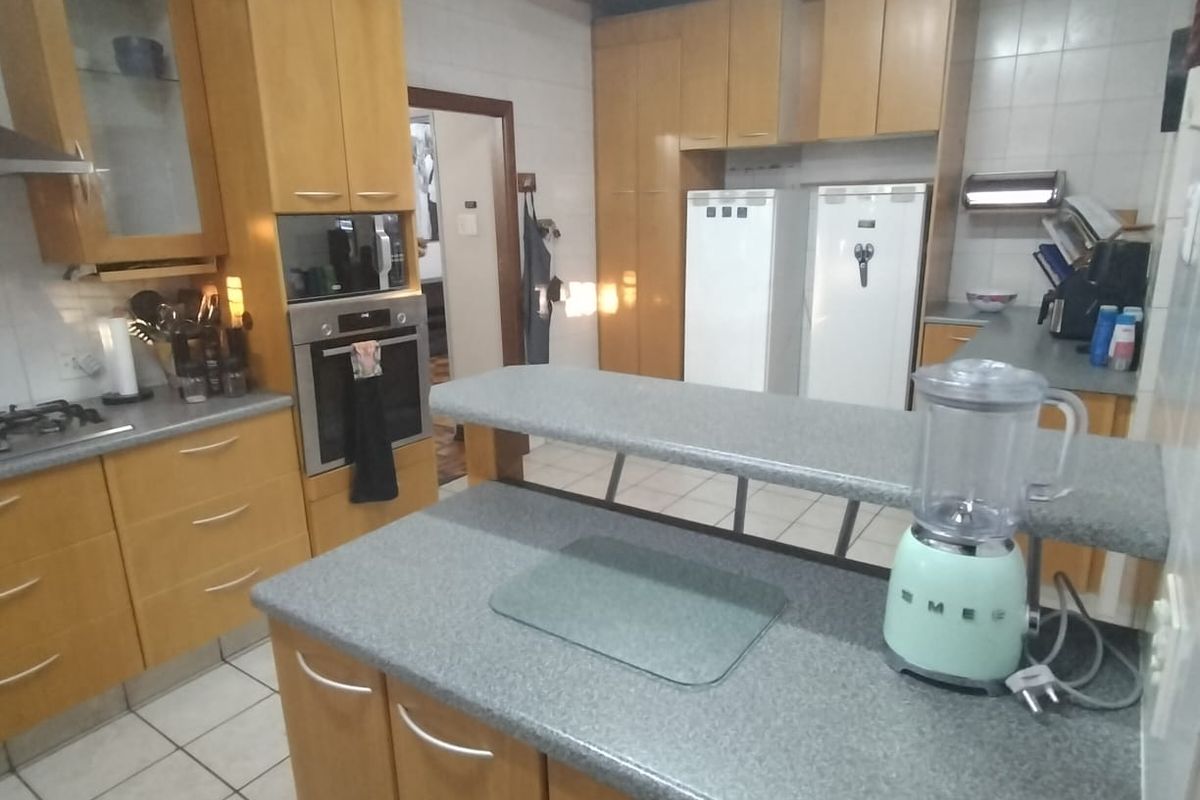 A functional kitchen featuring wooden cabinetry, a breakfast bar, built-in oven, and tiled flooring, offering a practical layout for daily meal preparation.