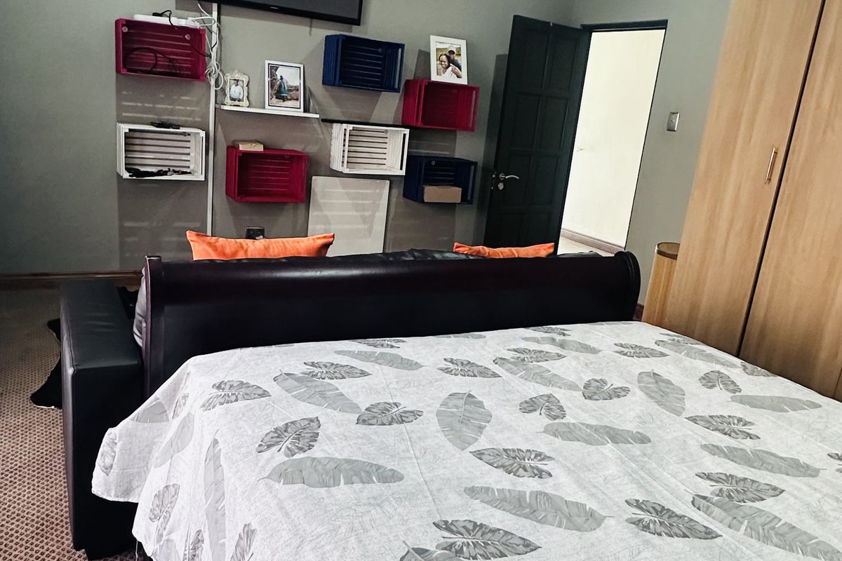 A bedroom featuring built-in wooden cabinetry, carpeted flooring, and a wall-mounted television setup.