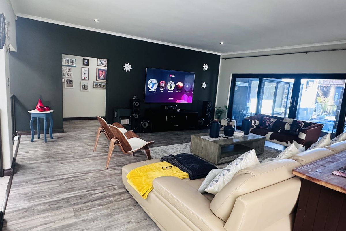 Spacious living room featuring dark accent wall, wood-look laminate flooring, and large sliding glass doors providing access to the outdoor area.
