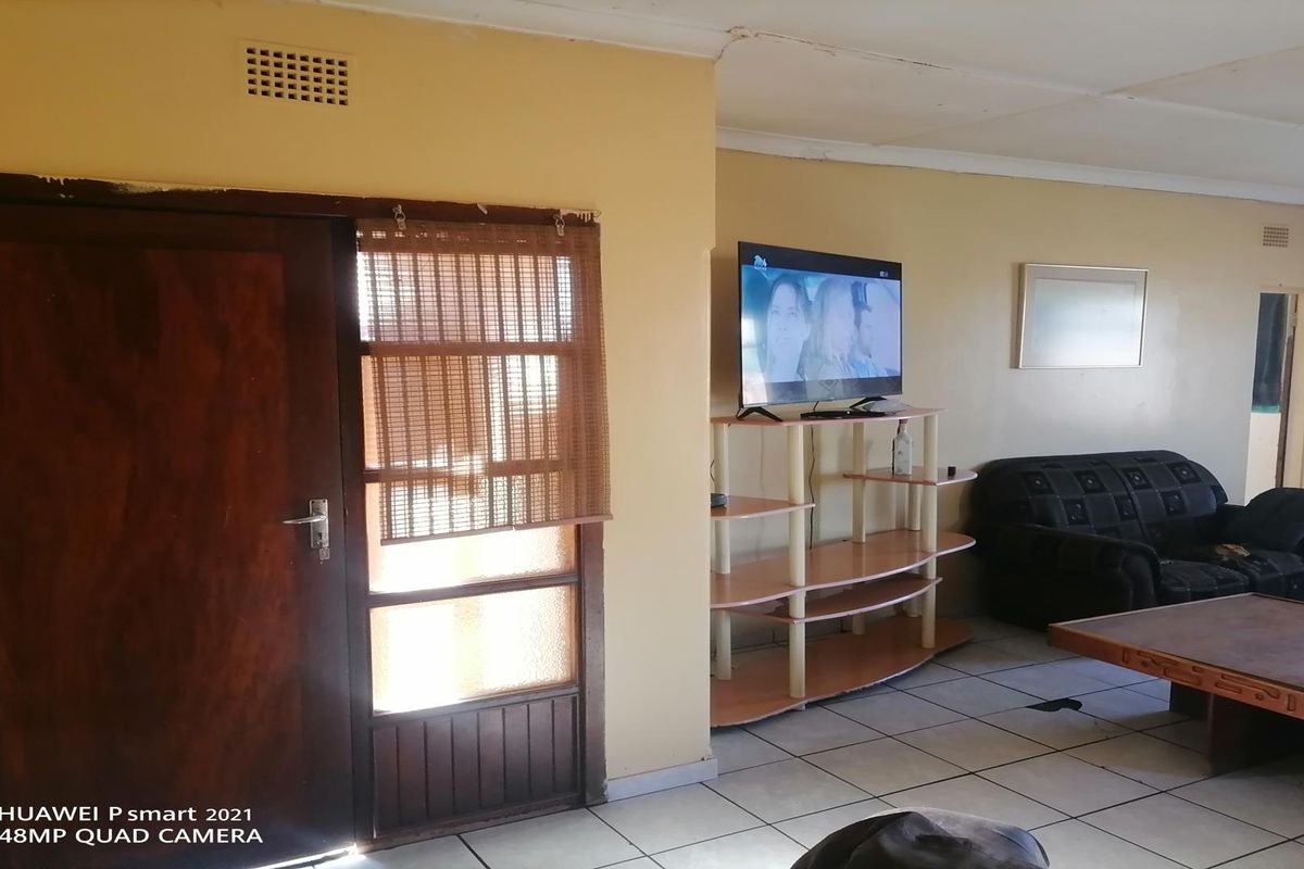A living area featuring tiled flooring, a wooden door with glass panels, and a ceiling vent.