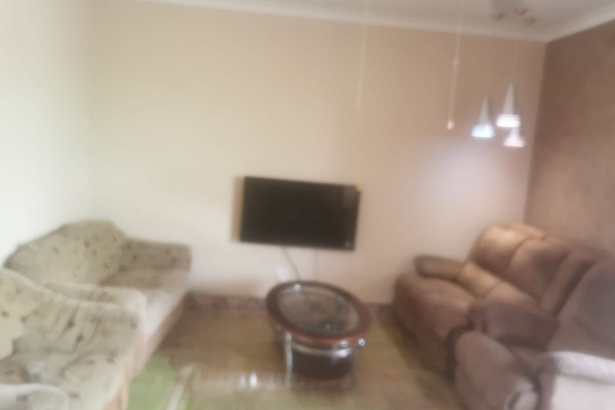 A living room area featuring a wall-mounted television and pendant lighting.