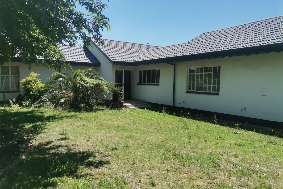 A view of the rear exterior of the house featuring a tiled roof, white plastered walls, and a garden area.