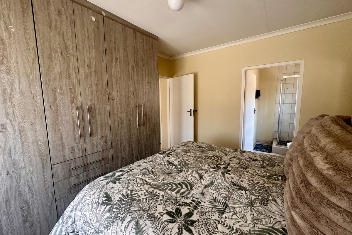 A bedroom featuring built-in wooden cabinetry and an en-suite bathroom entrance.