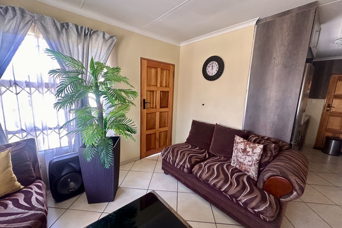 A living area featuring tiled flooring, a wooden panel door, and a neutral wall finish, providing a functional and accessible space.