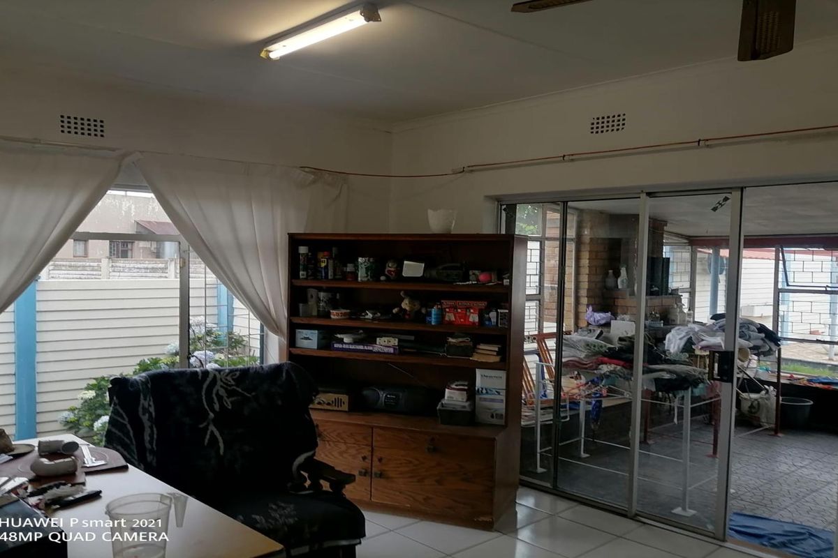 A living area featuring tiled flooring, sliding glass doors leading to an enclosed patio, and exposed surface-mounted electrical wiring.