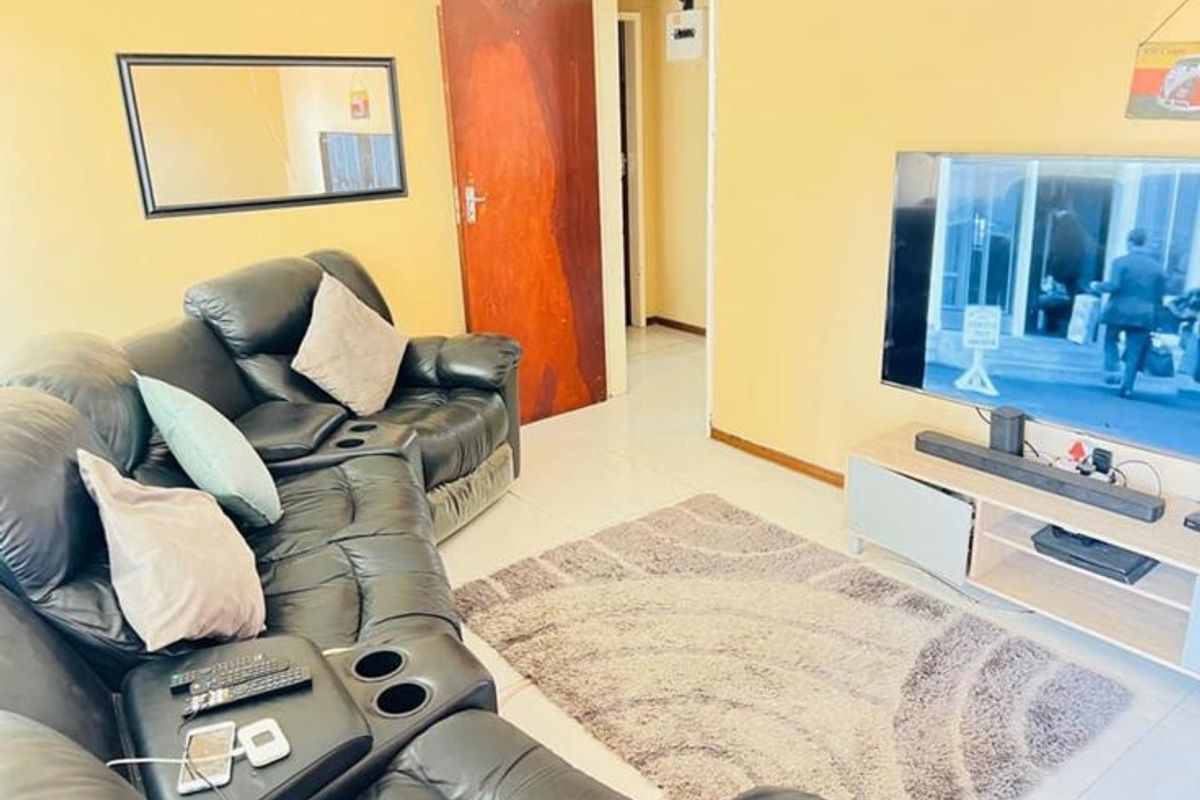 A living room featuring tiled flooring and a doorway leading to an adjacent hallway.