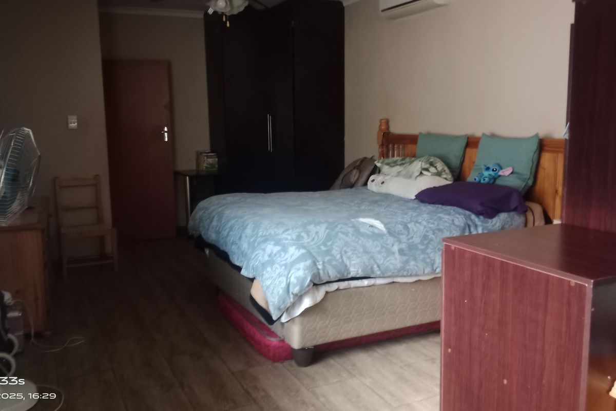 A bedroom featuring wood-look flooring, a wall-mounted air conditioning unit, and a built-in wardrobe.