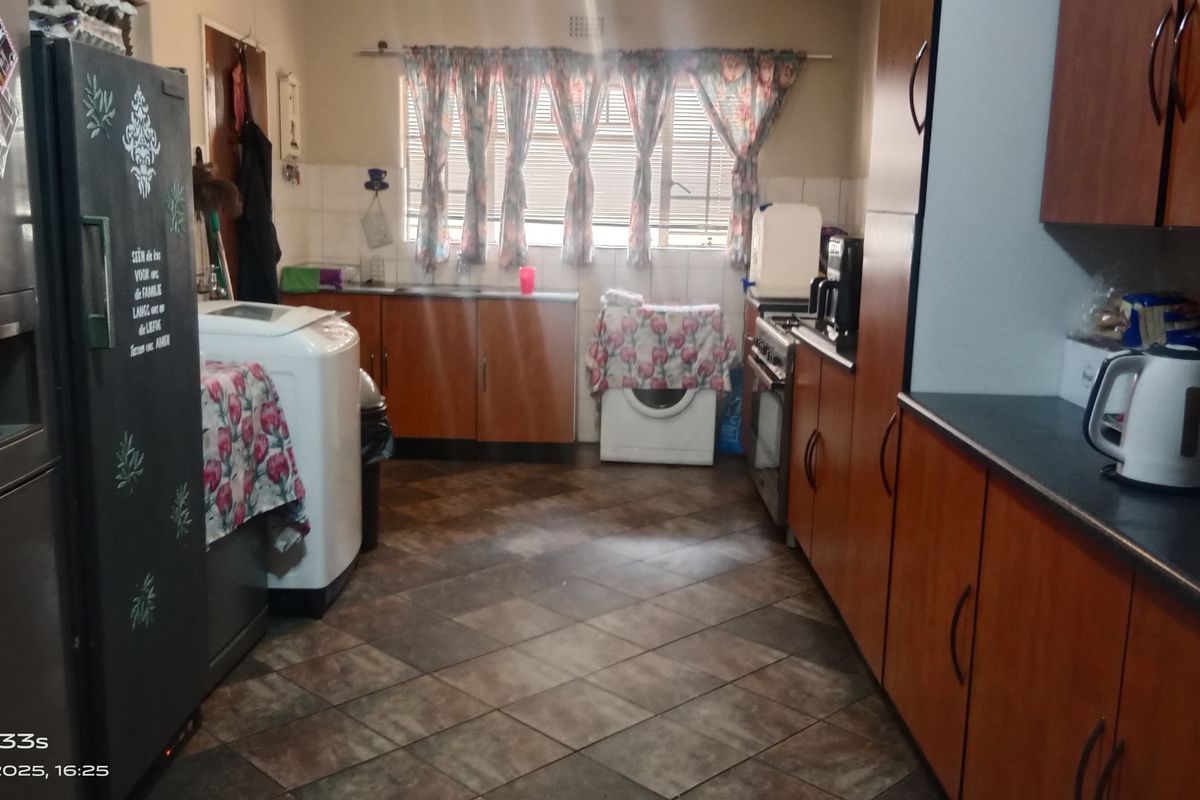 Functional kitchen featuring wood-look cabinetry, tiled flooring, and integrated appliance spaces, offering a practical layout for daily meal preparation.