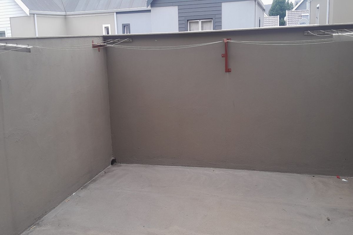 A functional outdoor utility area featuring concrete flooring and wall-mounted retractable clotheslines, suitable for laundry drying or storage.