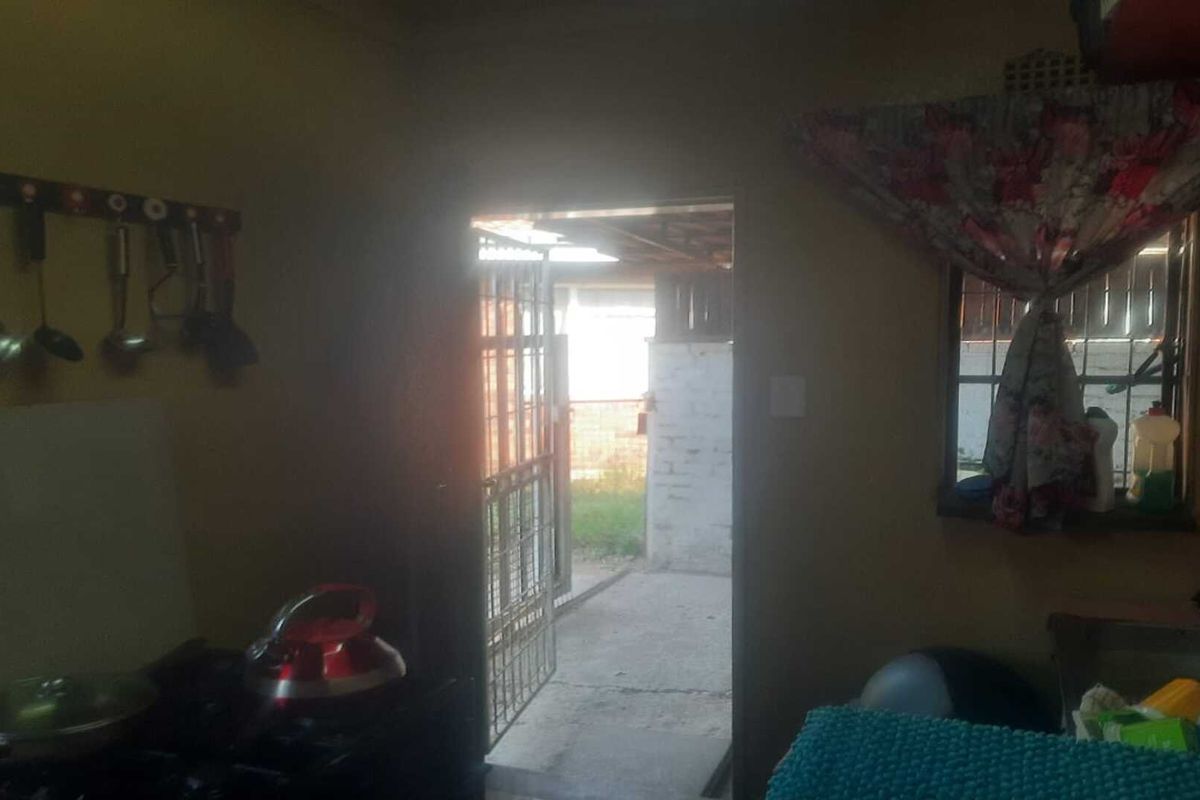 A functional kitchen area featuring a built-in stove and direct access to the exterior through a security gate.