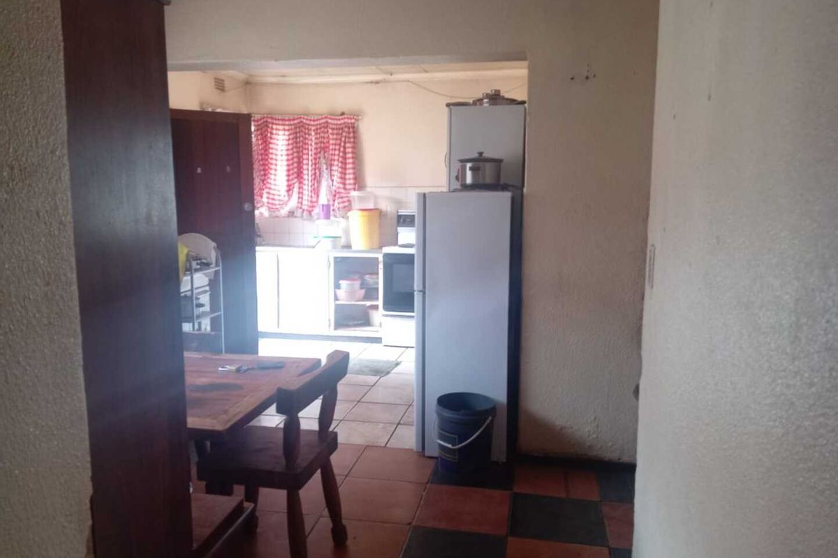 A functional kitchen area featuring tiled flooring and built-in cabinetry, viewed from an adjacent dining space.