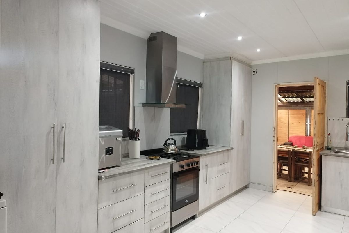 Modern kitchen featuring light wood-grain cabinetry, stainless steel oven and extractor fan, tiled flooring, and recessed ceiling lighting.