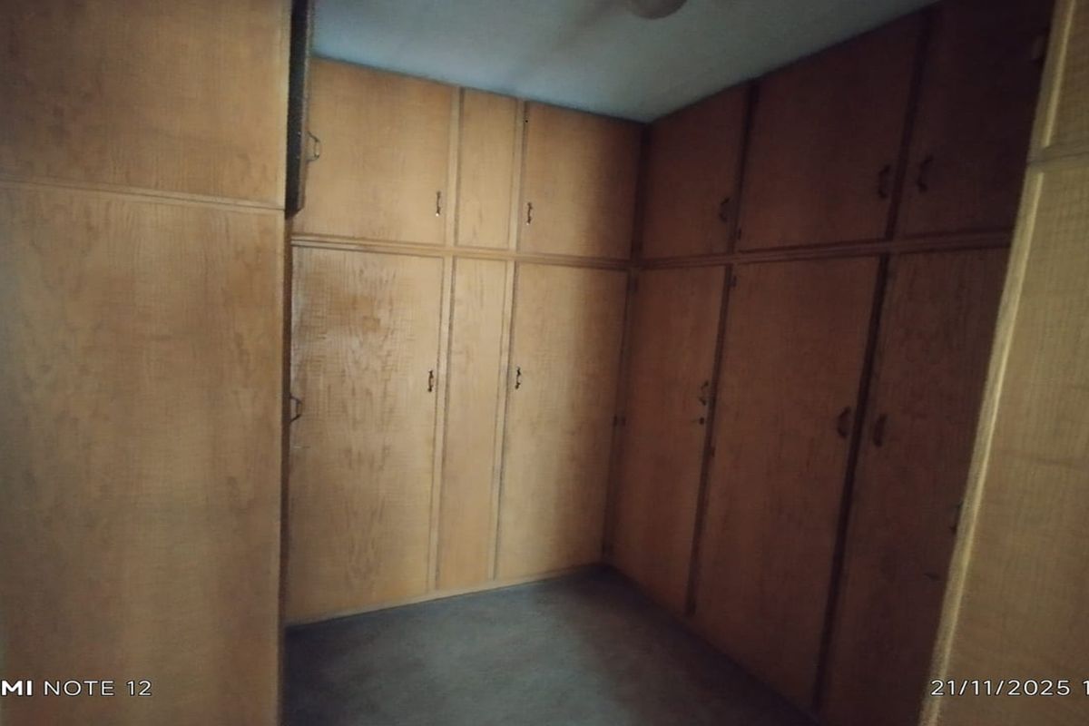 A bedroom featuring extensive floor-to-ceiling built-in wooden cupboards providing ample storage space.