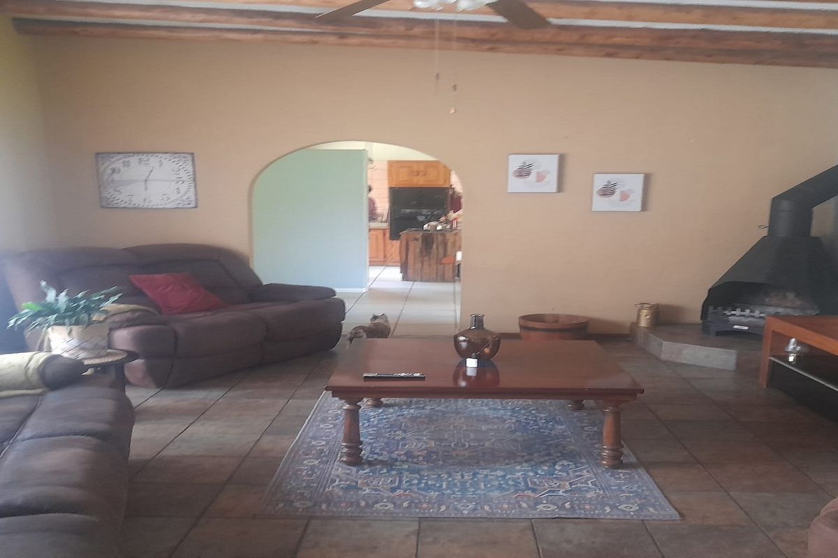 Spacious living room featuring exposed timber ceiling beams, tiled flooring, and a prominent freestanding fireplace with a flue.