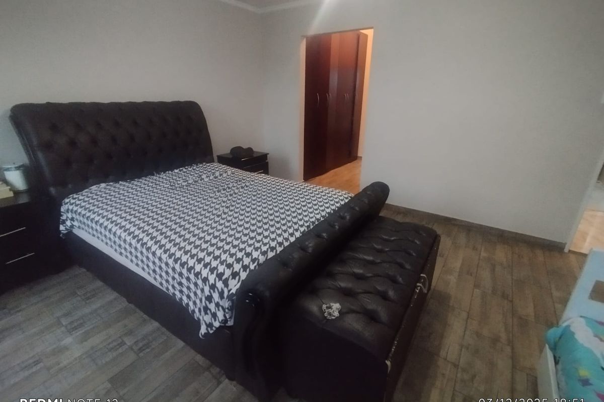 A bedroom featuring wood-look tiled flooring and built-in dark wood cabinetry in the adjacent dressing area.