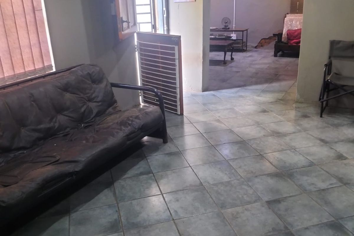A living area featuring tiled flooring and an open-plan layout leading to an adjacent room, with direct access to an exterior door.