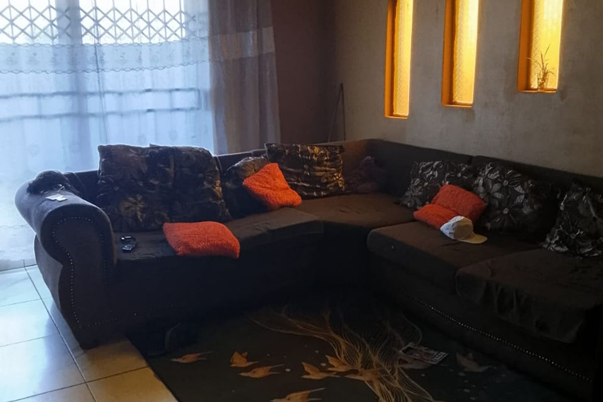 A living room featuring tiled flooring and decorative wall niches with integrated lighting, currently requiring ceiling completion and general maintenance.